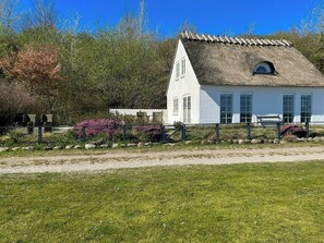A white building with a thatched roof, a bench, and a gate. - Summer house in fisherman's style by Helnæs Bay (Ebberup)