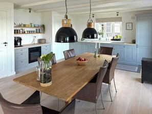 A spacious dining area with a wooden table, multiple chairs, and pendant lighting. - Summer house in fisherman's style by Helnæs Bay (Ebberup)
