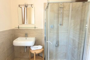 Ein Badezimmer mit einer gläsernen Duschkabine, einem Waschbecken und einem Spiegel.