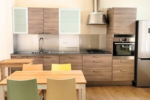 Eine moderne Küche mit Holzausbau, einer Edelstahl-Spüle, einem Gasherd und einem eingebauten Backofen.