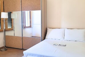 Ein Hotelzimmer mit Bett, Spiegel, Lampe und Fenster.