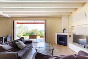 A living room with a sofa, a glass coffee table, a fireplace, and a television.