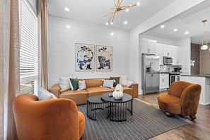 A modern living room with a sofa, two armchairs, a coffee table, and artwork on the wall. - The Stirrup | Walkable East Nashville (Nashville)