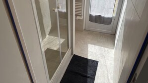 Une salle de bain avec une douche à parois de verre, un porte-serviettes et un rideau de douche.