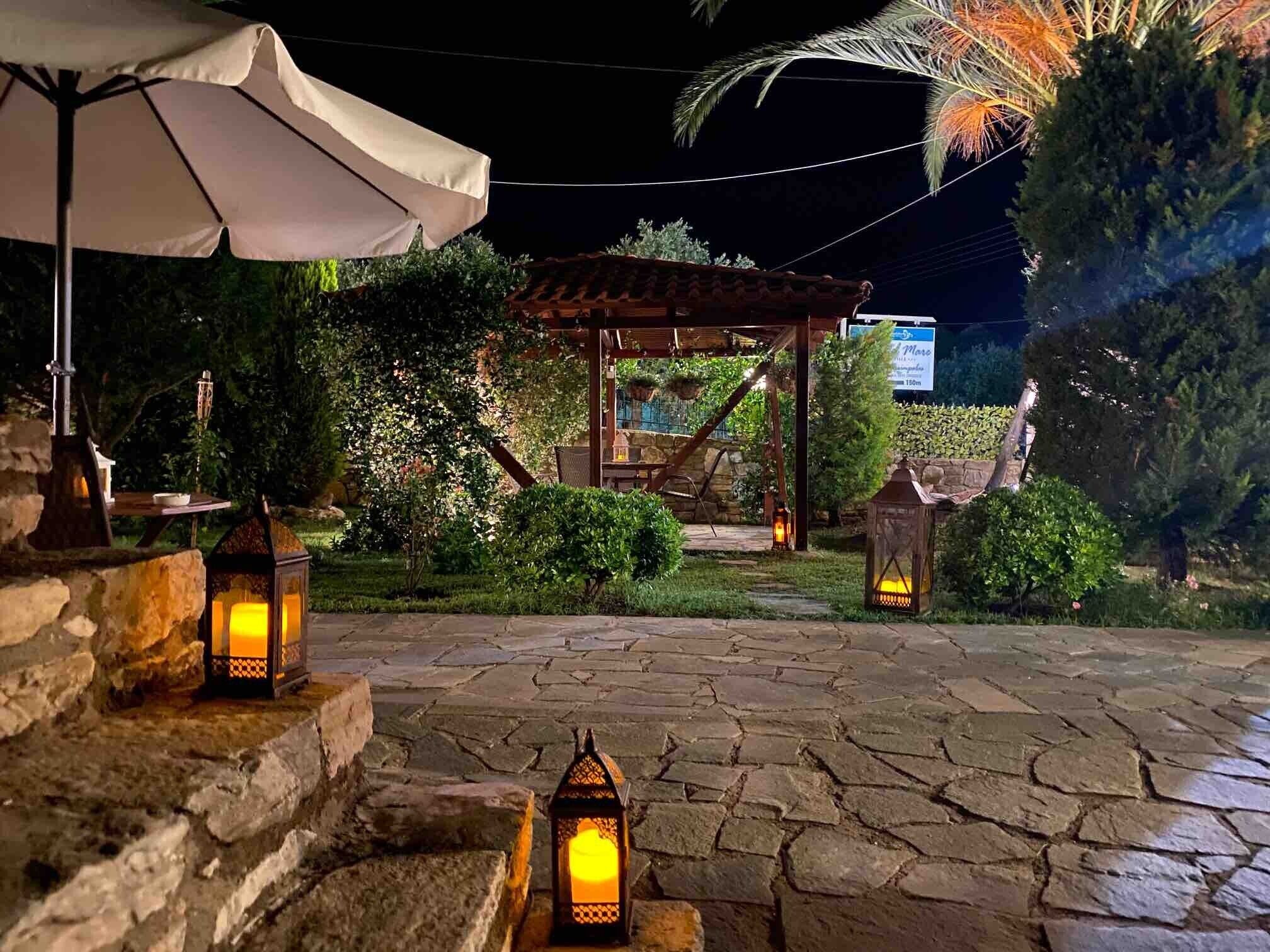 A stone-paved outdoor area with lanterns, a pergola, and a sign indicating a distance of 180m.