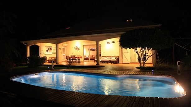 Ein Haus mit Schwimmbad, Sitzgelegenheiten im Freien und einer überdachten Terrasse.