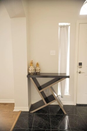 A room with a black console table, two decorative vases, a white door, and a window with curtains. - Spacious 4 Bedroom home with private backyard (Irving)