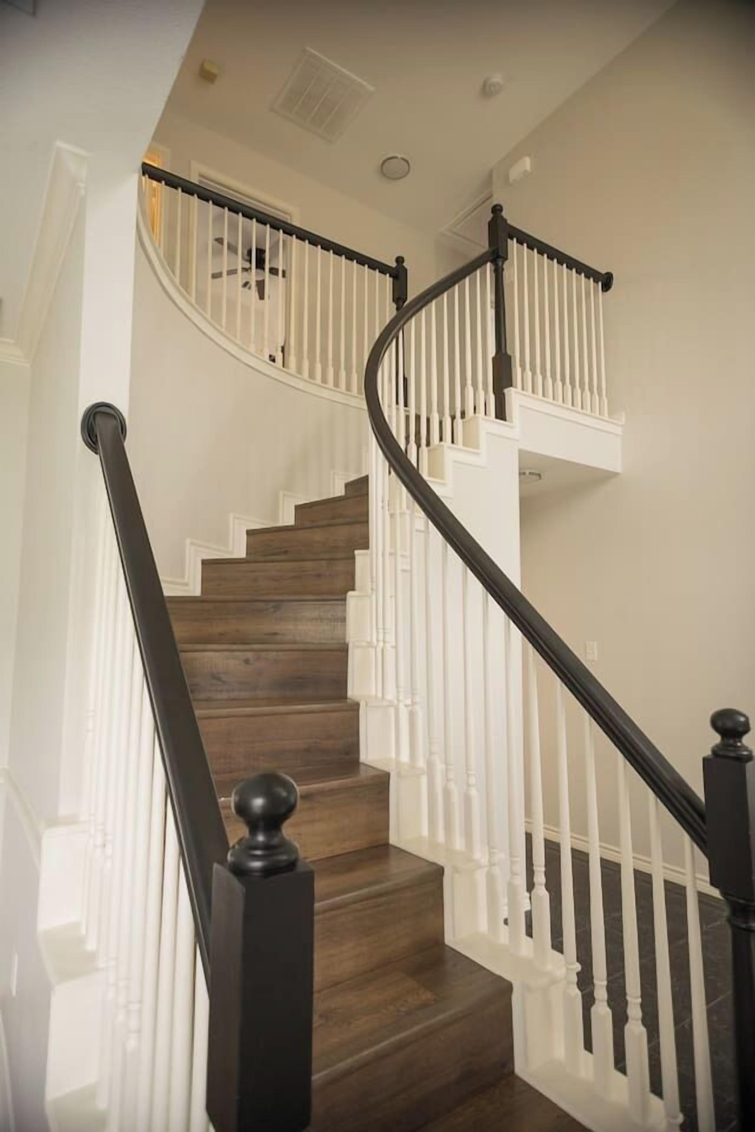 Un escalier en bois avec des rampes blanches et des balustres noires.