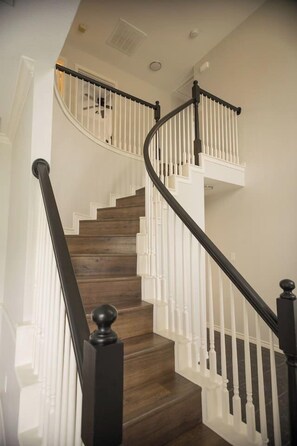 A wooden staircase with white railings and black balusters. - Spacious 4 Bedroom home with private backyard (Irving)