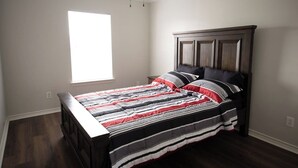 Ein Schlafzimmer mit einem Bett, einem Fenster und einem dunklen Holzkopfende.