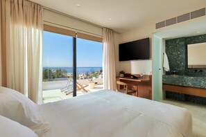 A hotel room with a large bed, a desk, a flat-screen TV, a bathroom with a marble countertop, and a balcony with a view of the sea. - The Nook Luxury Villa (Agia Pelagia)