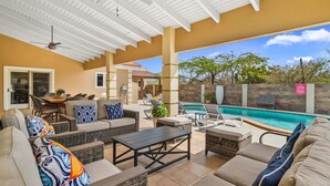 Um pátio ao ar livre com móveis de vime, piscina e vista para a paisagem circundante.