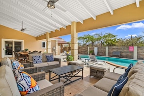 An outdoor patio with wicker furniture, a pool, and a view of the surrounding landscape. - Private Pool · BBQ · Gorgeous Pool (Noord)