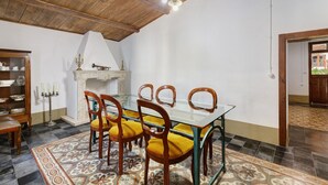 Un comedor con mesa de vidrio, sillas de madera, alfombra estampada y chimenea.