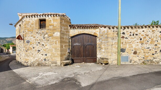 Un edificio de piedra con una puerta de madera grande y una ventana pequeña.