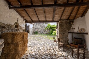 Un rústico edificio de piedra con techo de paja, pared de piedra y suelo de adoquines.