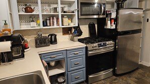 A kitchen with a stove, microwave, refrigerator, and various utensils.