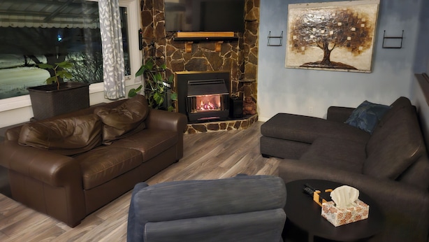 A living room with a stone fireplace, leather sofas, a flat-screen TV, and a painting on the wall.
