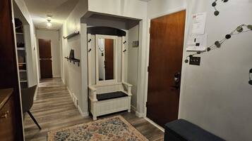 A hallway with a bench, a rug, and a mirror.