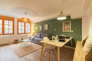 Ein modernes Wohnzimmer mit Sofa, Esstisch und Blick durch große Fenster.