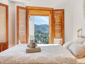 A bedroom with a bed, a view of a balcony, and a mountain landscape. - Casa Lavender Frigiliana - A peaceful retreat bathed in light (Frigiliana)