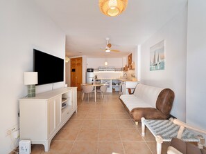 A living room with a TV, sofa, and dining area. - Casa Lavender Frigiliana - A peaceful retreat bathed in light (Frigiliana)