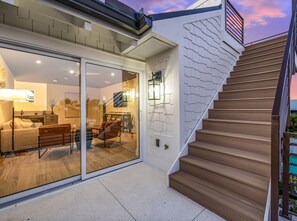 Ein modernes Haus mit Glastür, die zu einem Wohnbereich führt, einer Holztreppe und einem gefliesten Boden.