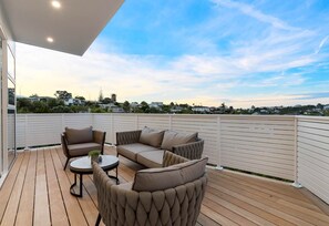 A rooftop deck with a sofa set, a small table, and a potted plant. - Charming 3-bedroom House With Ocean Views in Auckland (Auckland)
