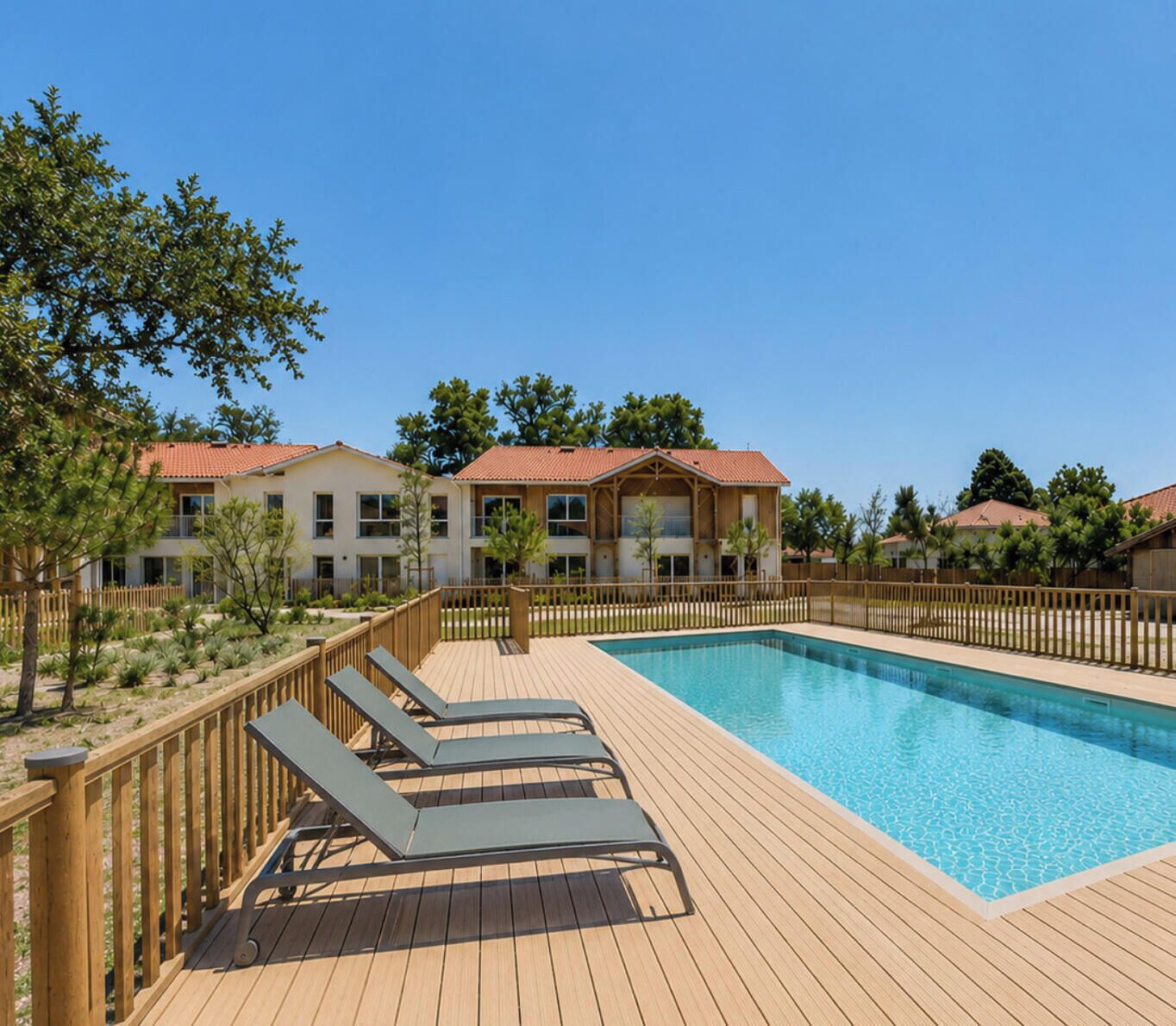 A swimming pool with lounge chairs, a wooden deck, and a building with a red roof in the background.