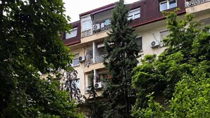 A multi-story residential building with balconies, surrounded by greenery and a paved walkway. - Cozy studio free public parking, near to City Center, Main train and bus station (Skopje)
