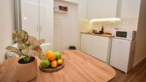 A modern kitchen with white cabinets, a microwave, and a small refrigerator. - Cozy studio free public parking, near to City Center, Main train and bus station (Skopje)