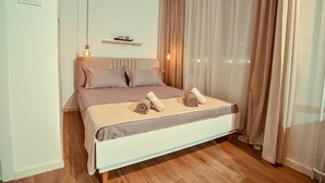 A modern bedroom with a bed, curtains, a shelf, and a hanging light. - Cozy studio free public parking, near to City Center, Main train and bus station (Skopje)