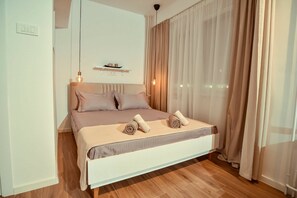 A modern bedroom with a bed, curtains, a shelf, and a hanging light. - Cozy studio free public parking, near to City Center, Main train and bus station (Skopje)