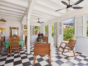 A room with a checkered floor, wooden chairs, a dining table with a green tablecloth, and a ceiling fan. - House for 7 with terrace, 100 m from sea (Les Anses-d´Arlet)