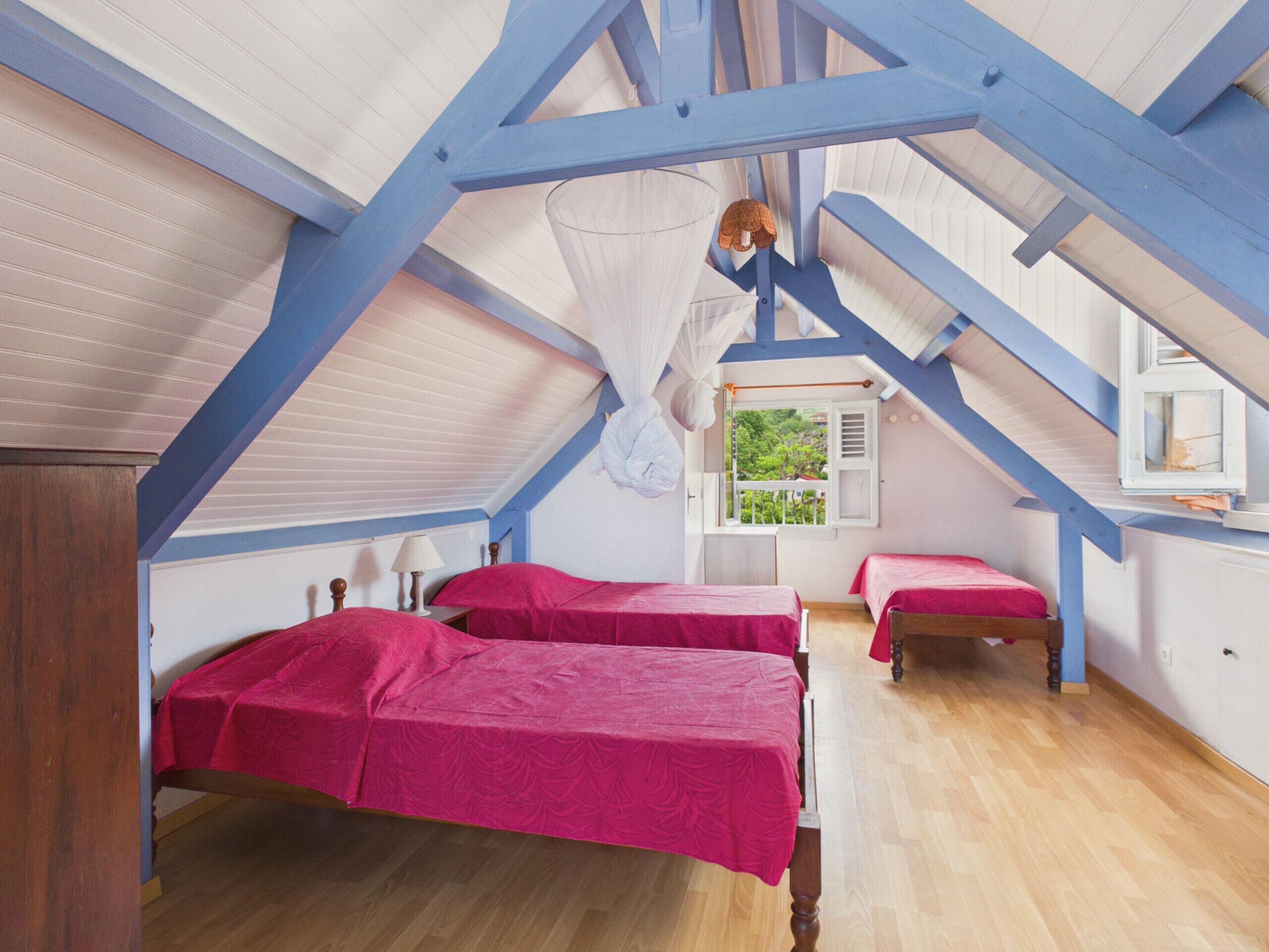 Un dormitorio con dos camas, una ventana y techo inclinado.