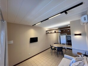 Una cucina con zona pranzo, una TV a schermo piatto montata a parete e un frigorifero.