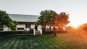 A white building with a flat roof, a front porch, and a well-maintained lawn.