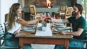 A dining table with chairs, a fireplace, and hanging light fixtures.