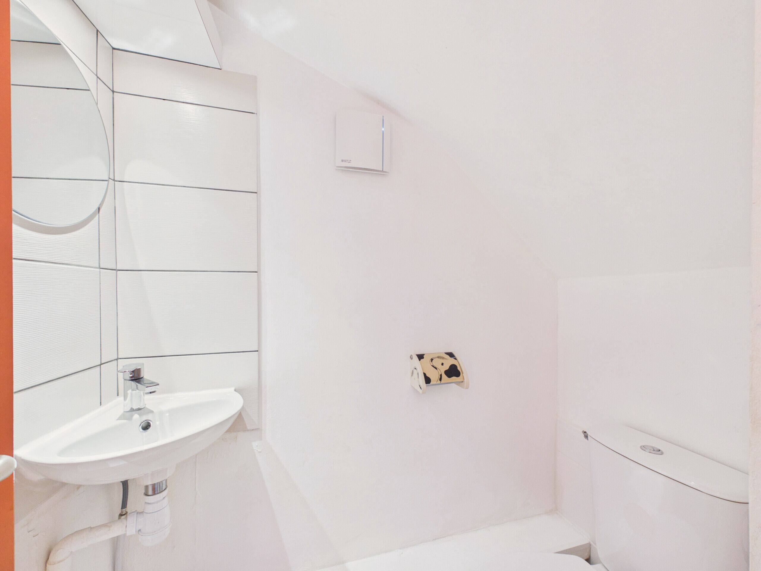 Une salle de bain avec un lavabo blanc, un miroir et des toilettes.
