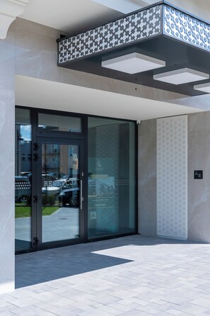 Une entrée moderne avec une porte en verre, un plafond orné de motifs et un sol carrelé.