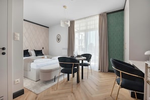 Une chambre d’hôtel moderne équipée d’un lit, d’un bureau, de deux chaises, d’une petite table et d’une fenêtre avec des rideaux.