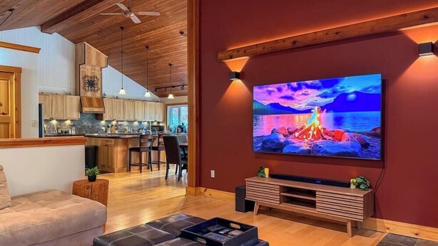 Ein modernes Wohnzimmer mit einem großen Flachbildfernseher, Holzböden und einer gemütlichen Sitzecke.