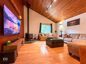 Ein gemütliches Wohnzimmer mit Kamin, Sofas und einem an der Wand befestigten Fernseher.