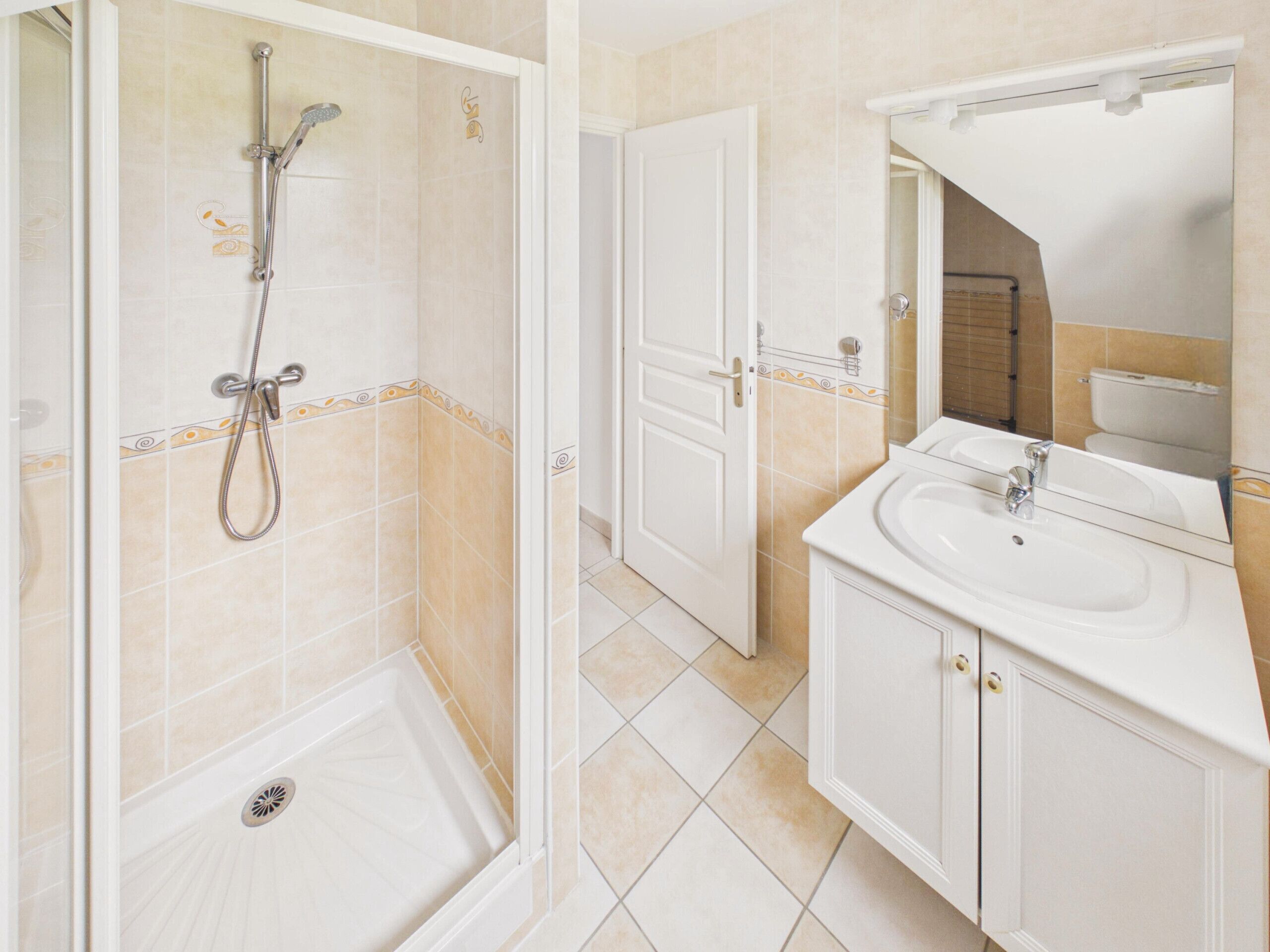 A bathroom with a shower, toilet, sink, and mirror.