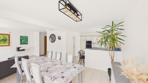 Ein moderner Essbereich mit Tisch, Stühlen, einer Uhr und einer Küche im Hintergrund.