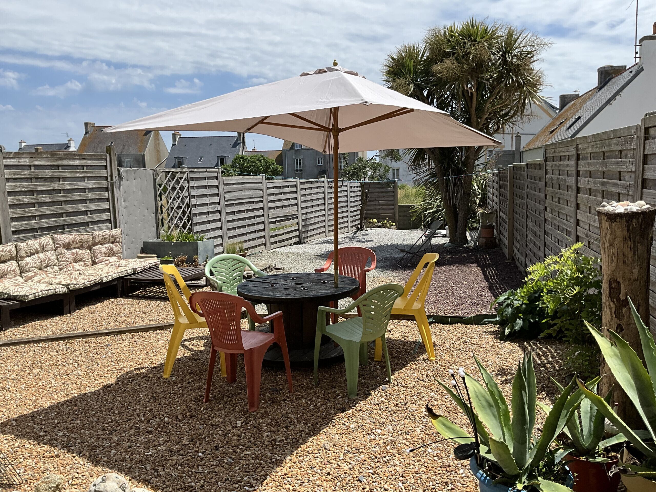 Un espace extérieur aménagé avec une table, des chaises et un grand parasol.