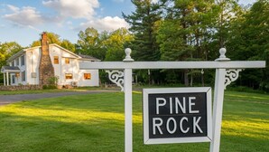 A sign with 'Pine Rock' written on it, a white house with a stone chimney, and a well-maintained lawn. - Ohiopyle Weddings, Family Getaway, Bridal Party (Ohiopyle)