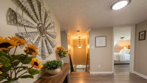 A hallway with a wooden bench, a decorative wall piece, and a staircase leading to a bedroom. - Ohiopyle Weddings, Family Getaway, Bridal Party (Ohiopyle)