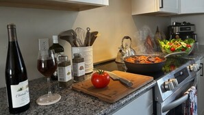 A kitchen with a stove, a cutting board with a tomato, a wine bottle, and a glass. - Ohiopyle Weddings, Family Getaway, Bridal Party (Ohiopyle)