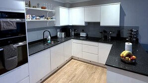 Eine moderne Küche mit weißen Schränken, einer schwarzen Arbeitsplatte und Holzboden.